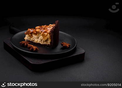 Delicious fresh cheesecake cake or snickers with cream and nuts on a ceramic plate on a dark concrete background