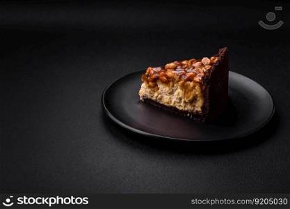 Delicious fresh cheesecake cake or snickers with cream and nuts on a ceramic plate on a dark concrete background