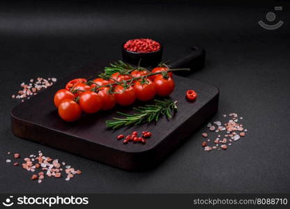 Delicious fresh cherry tomatoes on a twig on a dark concrete background. Vegetarian cooking