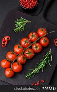 Delicious fresh cherry tomatoes on a twig on a dark concrete background. Vegetarian cooking