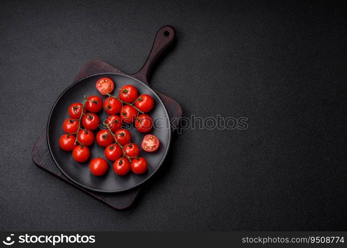 Delicious fresh cherry tomatoes on the branches as an ingredient for cooking a vegetarian dish on a dark concrete background