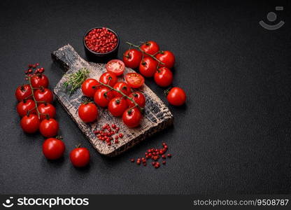 Delicious fresh cherry tomatoes on the branches as an ingredient for cooking a vegetarian dish on a dark concrete background