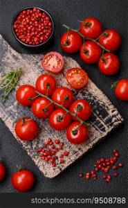 Delicious fresh cherry tomatoes on the branches as an ingredient for cooking a vegetarian dish on a dark concrete background