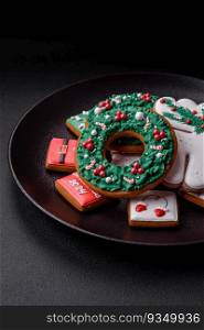Delicious fresh colorful Christmas or New Year gingerbread cookies on a ceramic plate on a dark concrete background