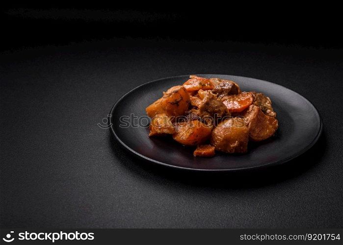 Delicious fresh cooked stew with pork meat or beef with potatoes, carrots, spices and herbs on a dark concrete background