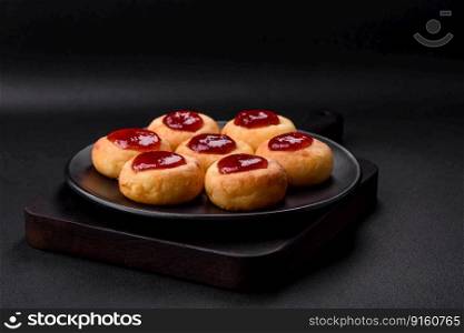 Delicious fresh cottage cheesecakes with raisins and vanilla on a black ceramic plate on a dark concrete background
