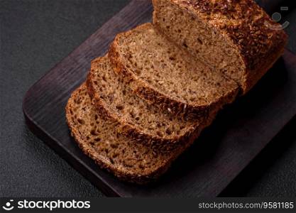 Delicious fresh crispy brown bread with grains and seeds on a dark concrete background