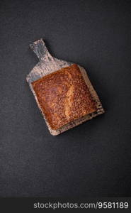 Delicious fresh crispy brown bread with grains and seeds on a dark concrete background