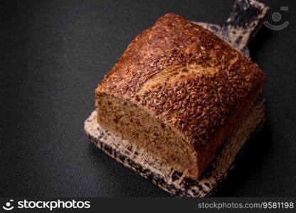 Delicious fresh crispy brown bread with grains and seeds on a dark concrete background