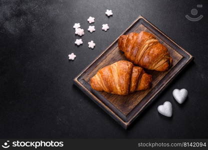 Delicious fresh crispy croissants on a dark concrete background. Tasty breakfast. Delicious fresh crispy croissants on a dark concrete background