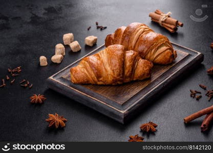 Delicious fresh crispy croissants on a dark concrete background. Tasty breakfast