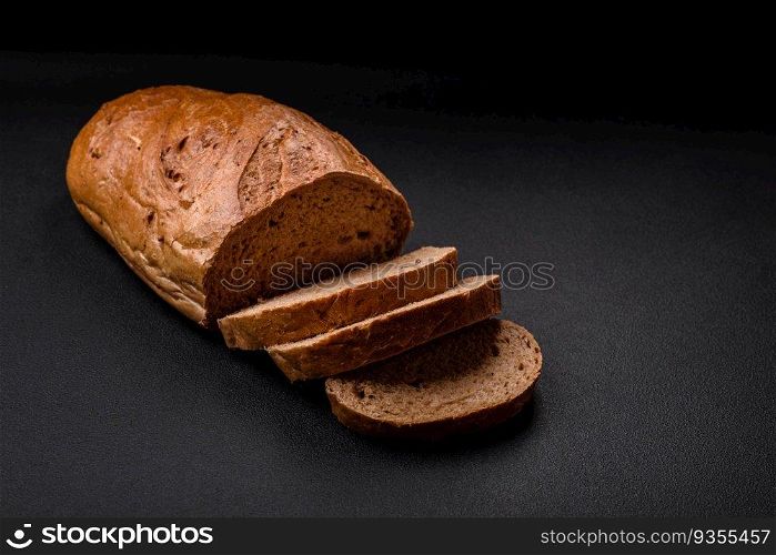 Delicious fresh crispy loaf of white bread with grains and seeds on a textural dark background. Delicious fresh crispy loaf of white bread with grains and seeds