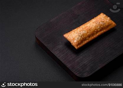 Delicious fresh crispy pie with cherry jam on a wooden cutting board on a dark concrete background