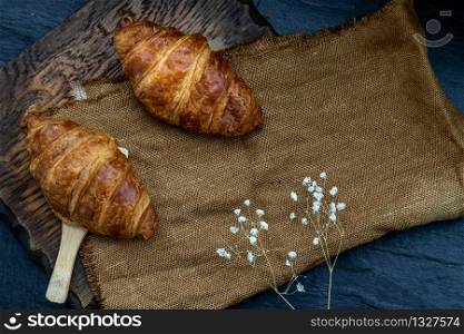 Delicious fresh croissants placed on a wooden plate ready to eat. A delicious French breakfast. Top view, Place for text.
