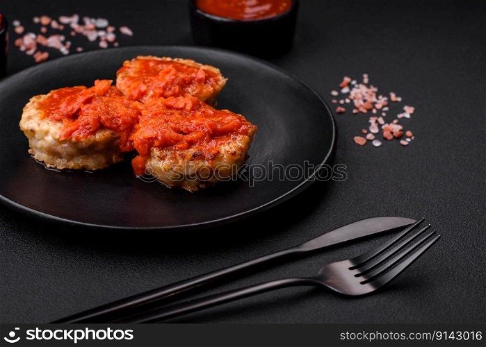 Delicious fresh cutlets or meatballs with spices, herbs and tomato sauce on a dark concrete background