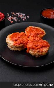 Delicious fresh cutlets or meatballs with spices, herbs and tomato sauce on a dark concrete background