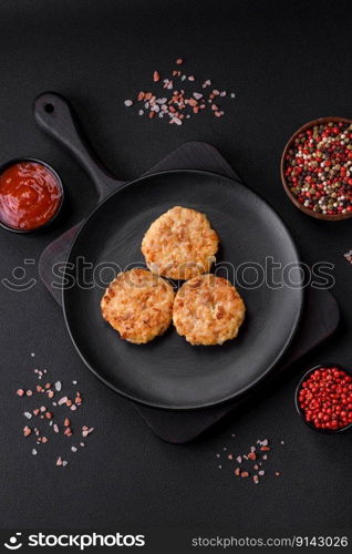 Delicious fresh cutlets or meatballs with spices, herbs and tomato sauce on a dark concrete background