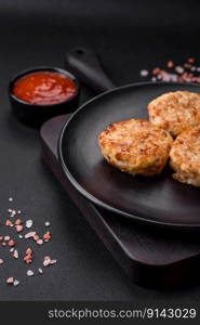 Delicious fresh cutlets or meatballs with spices, herbs and tomato sauce on a dark concrete background