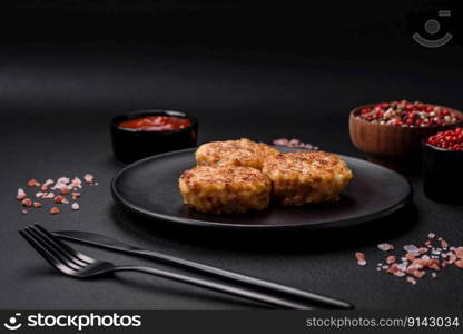 Delicious fresh cutlets or meatballs with spices, herbs and tomato sauce on a dark concrete background