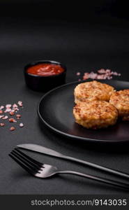 Delicious fresh cutlets or meatballs with spices, herbs and tomato sauce on a dark concrete background