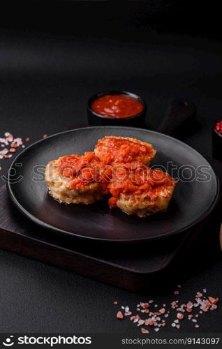 Delicious fresh cutlets or meatballs with spices, herbs and tomato sauce on a dark concrete background