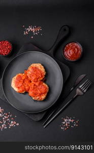 Delicious fresh cutlets or meatballs with spices, herbs and tomato sauce on a dark concrete background