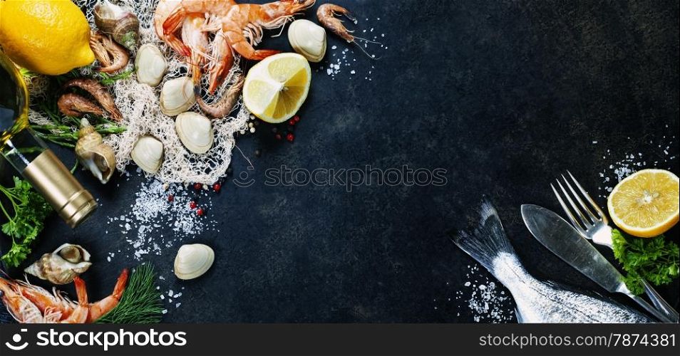 Delicious fresh fish and seafood on dark vintage background. Fish, clams and shrimps with aromatic herbs, spices and vegetables - healthy food, diet or cooking concept