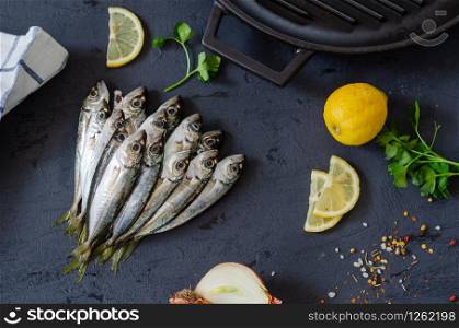 Delicious fresh fish , aromatic herbs, spices and lemon on the black background.Mediterranean cuisine. Top view. Healthy and diet food concept. Raw fish for cooking