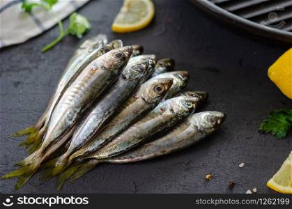 Delicious fresh fish , aromatic herbs, spices and lemon on the black background.Mediterranean cuisine. Top view. Healthy and diet food concept. Raw fish for cooking