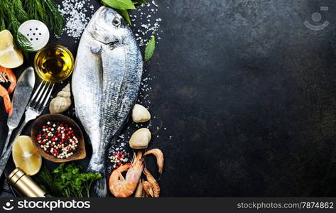 Delicious fresh fish on dark vintage background. Fish with aromatic herbs, spices and vegetables - healthy food, diet or cooking concept