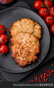 Delicious fresh fried minced chicken meat cutlets with salt, spices and herbs on a dark concrete background