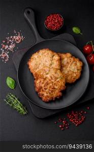 Delicious fresh fried minced chicken meat cutlets with salt, spices and herbs on a dark concrete background