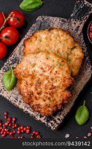 Delicious fresh fried minced chicken meat cutlets with salt, spices and herbs on a dark concrete background