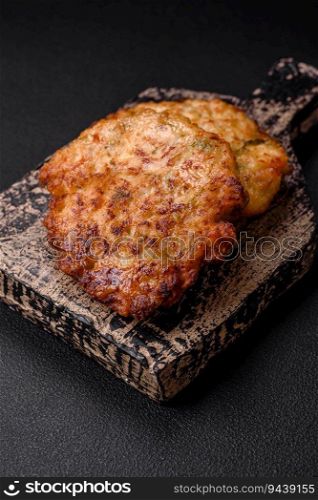Delicious fresh fried minced chicken meat cutlets with salt, spices and herbs on a dark concrete background