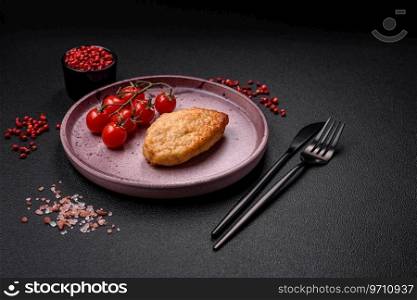 Delicious fresh fried vegetarian soybean cutlet with salt, spices and herbs with vegetables on a ceramic plate on a dark concrete background
