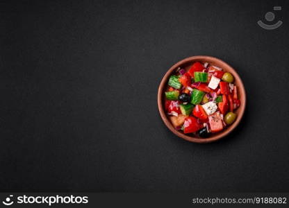 Delicious, fresh Greek salad with feta cheese, olives, tomatoes and cucumbers on a dark concrete background