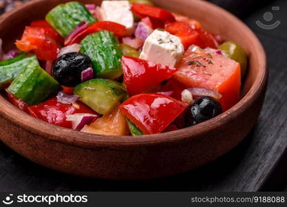 Delicious, fresh Greek salad with feta cheese, olives, tomatoes and cucumbers on a dark concrete background