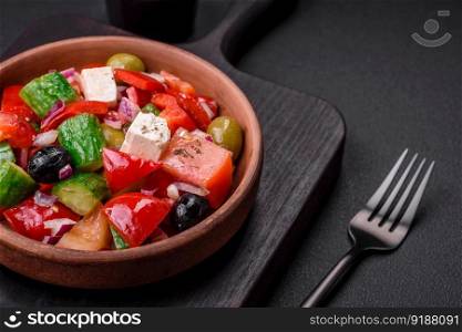 Delicious, fresh Greek salad with feta cheese, olives, tomatoes and cucumbers on a dark concrete background