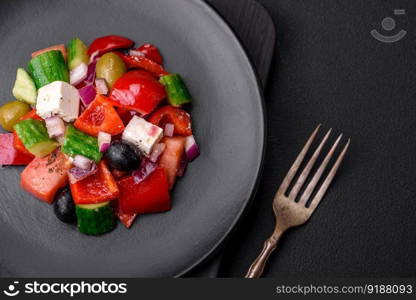 Delicious, fresh Greek salad with feta cheese, olives, tomatoes and cucumbers on a dark concrete background