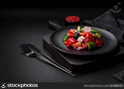 Delicious, fresh Greek salad with feta cheese, olives, tomatoes and cucumbers on a dark concrete background