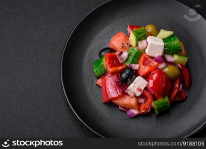 Delicious, fresh Greek salad with feta cheese, olives, tomatoes and cucumbers on a dark concrete background
