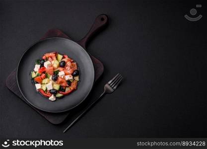 Delicious fresh Greek salad with olives, tomatoes, cucumbers, feta cheese, spices, herbs and olive oil on a black ceramic plate