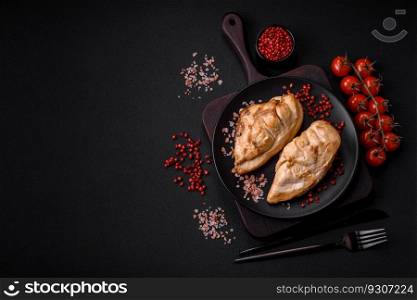 Delicious fresh grilled chicken fillet with salt, spices and herbs on a ceramic plate on a dark concrete background