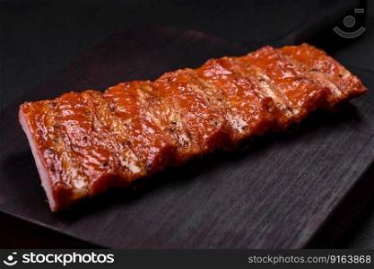 Delicious fresh grilled or smoked ribs with salt, spices and herbs on dark concrete background