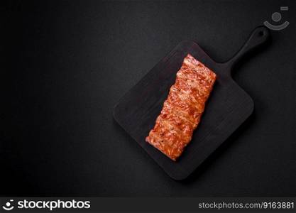 Delicious fresh grilled or smoked ribs with salt, spices and herbs on dark concrete background