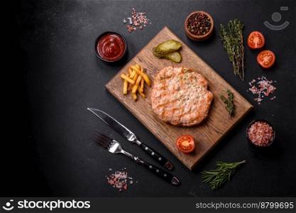Delicious fresh grilled turkey meat steak with spices and herbs on a dark concrete background
