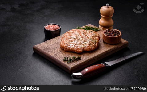 Delicious fresh grilled turkey meat steak with spices and herbs on a dark concrete background