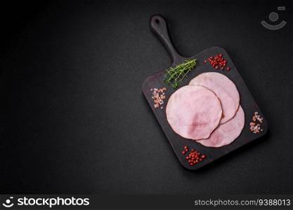 Delicious fresh ham cut into round slices with salt, spices and herbs on a dark concrete background