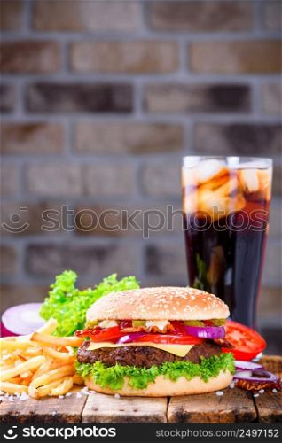 Delicious fresh hamburger with french fries and cola on wooden table