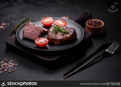 Delicious fresh juicy beef steak with spices and herbs on a dark concrete background. Grilled dish